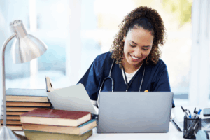 Nursing Student Studies at Desk with Laptop and Books