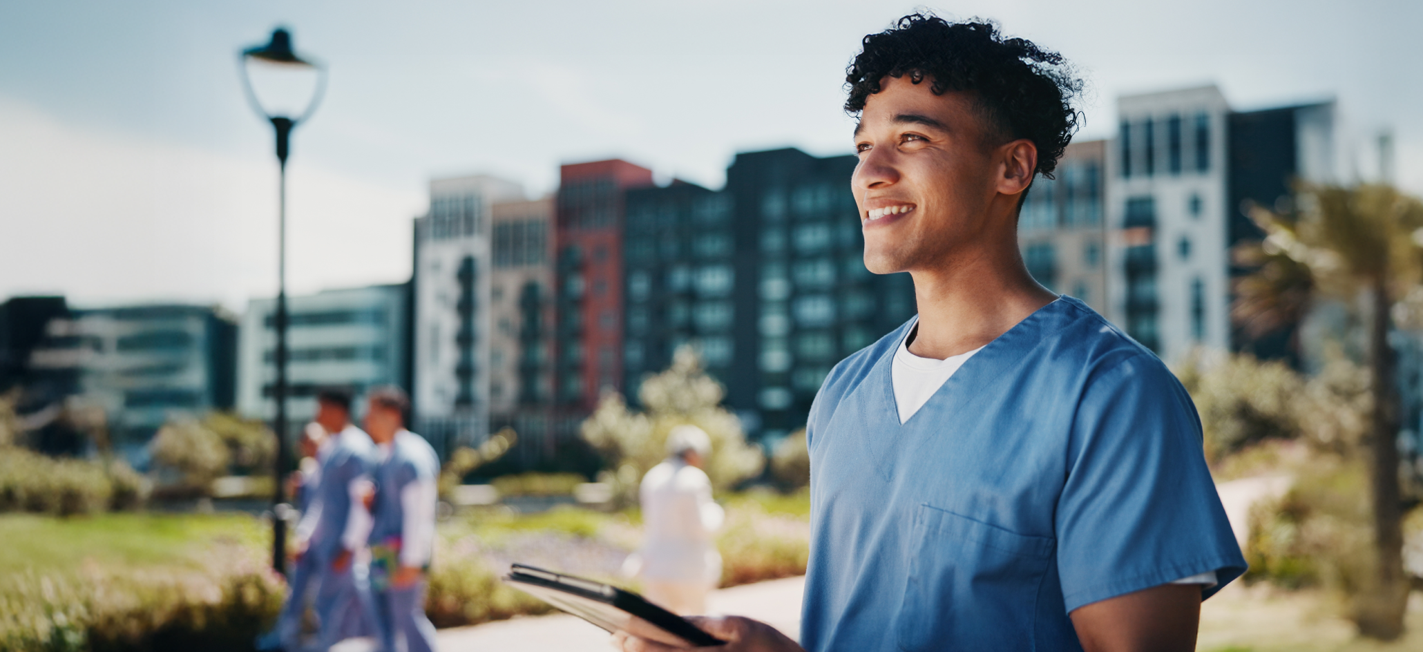 Healthcare Worker Stands Outside with Tablet Smiling